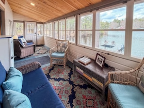A cozy room with a large window, wicker furniture, and a rug. - Lakefront Cabin - Private Dock, Hot Tub & Fire Pit (Barrington)