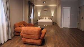 Une chambre d’hôtel avec un grand lit, un canapé, une petite table et une porte.