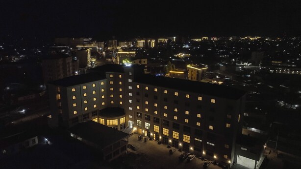 Un hôtel à plusieurs étages doté d’une cour intérieure, de fenêtres illuminées et d’une entrée imposante.