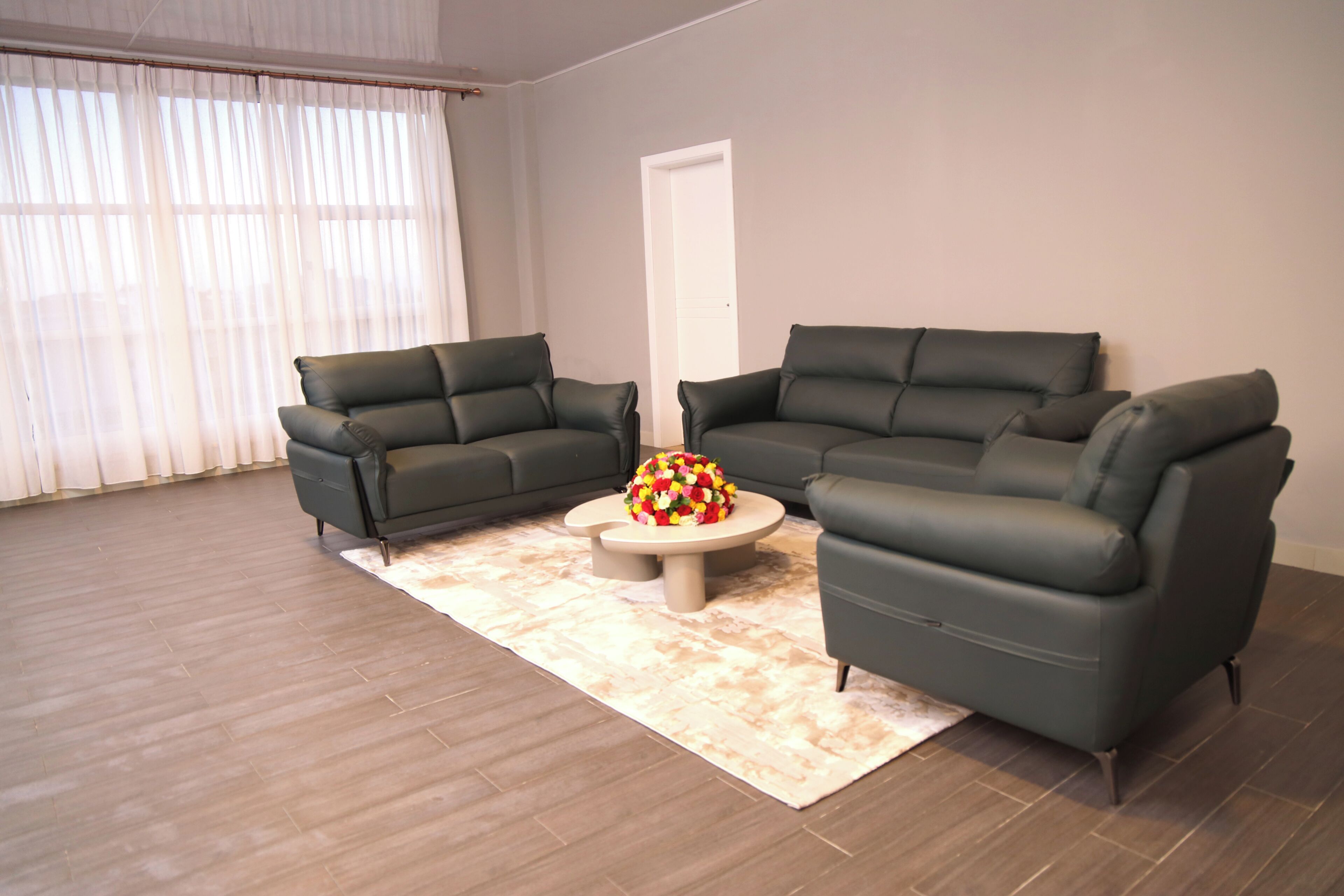 A living room with two dark sofas, a coffee table, and a door in the background.