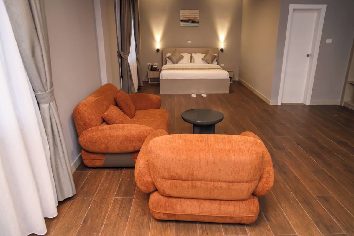 A bedroom with a bed, two nightstands, a bedside table, and a sofa.