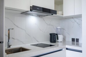 Eine moderne Küche mit Einbauherd, einer schwarzen Kaffeemaschine und einem Mixer auf der Arbeitsfläche.