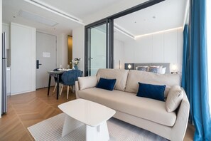 Ein modernes Hotelzimmer mit einer Couch, einem Esstisch und einem großen Fenster.