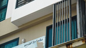 A multi-story building with balconies, a visible sign, and a window with bars. - Room-cozy Old Town Room 5 min Walk Local (Phuket)