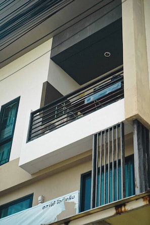 A multi-story building with balconies, a visible sign, and a window with bars. - Room-cozy Old Town Room 5 min Walk Local (Phuket)