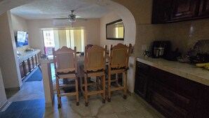 A kitchen with wooden chairs, a dining table, and a ceiling fan. - Cozy 1-bedroom condo in fantastic San José del Cabo with AC. Close to the beach (San José del Cabo)