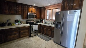 A kitchen with wooden cabinets, a stainless steel refrigerator, a microwave, an oven, and a coffee maker. - Cozy 1-bedroom condo in fantastic San José del Cabo with AC. Close to the beach (San José del Cabo)