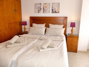 Un lit bien fait, avec une literie à rayures, une tête de lit en bois et deux tables de chevet avec des lampes.