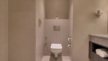 A modern bathroom with a toilet, shower, and vanity.