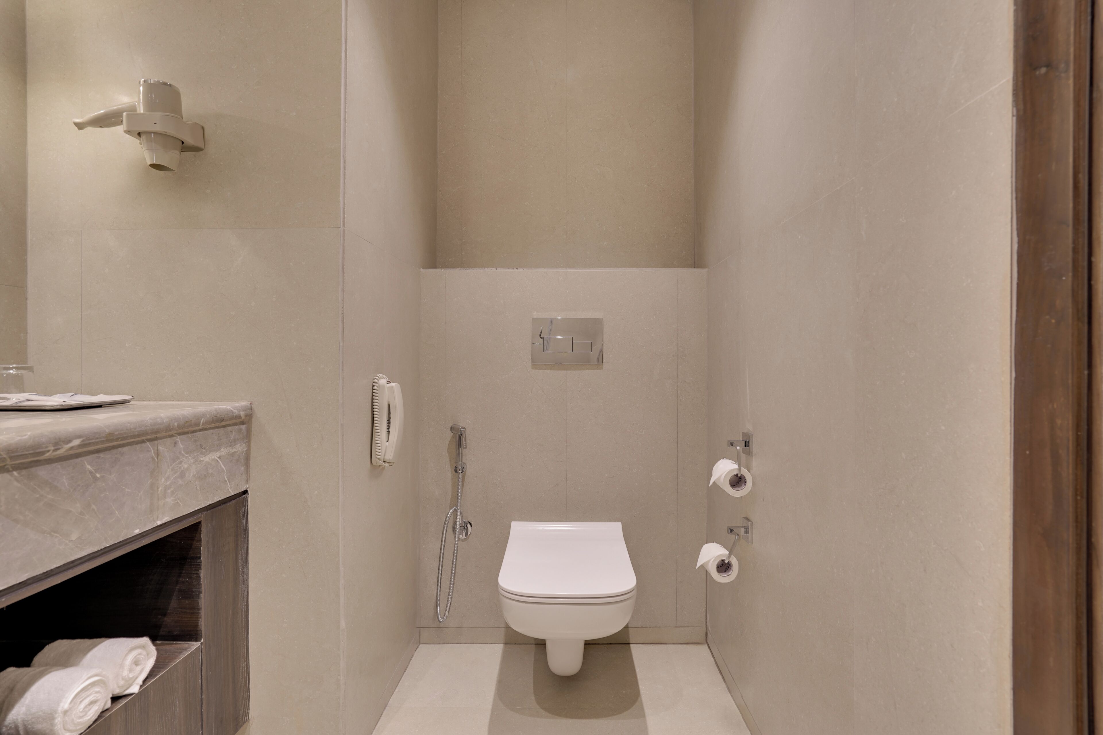 A bathroom with a toilet, a shower, and a marble countertop with a towel rack.