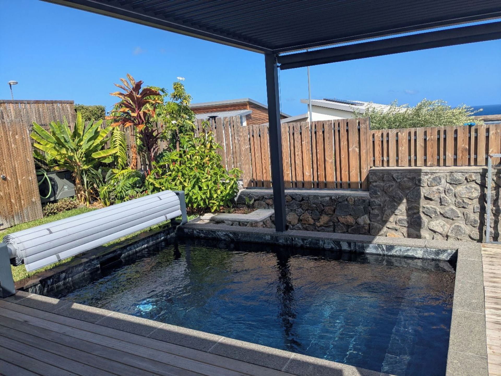 Une piscine dotée d’une terrasse en bois, d’escaliers en pierre et d’une clôture en bois.