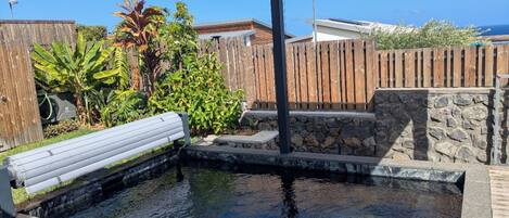 Une piscine dotée d’une terrasse en bois, d’escaliers en pierre et d’une clôture en bois.