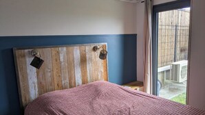 A room with a bed, a wooden headboard, a window with a view, and an air conditioning unit. - 3* family villa - Walking distance to the lagoon - Heated pool - Saint-Leu (Saint-Leu)