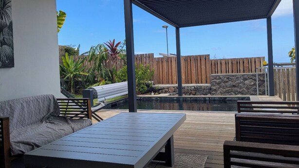 An outdoor patio with a pool, wooden deck, and seating area. - 3* family villa - Walking distance to the lagoon - Heated pool - Saint-Leu (Saint-Leu)