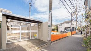 A building with a gated entrance, a covered area with tables, and a street with a parked motorcycle. -  Asagaya Room B｜1R｜10 Min to Shinjuku｜Budget Studio for 2 (Suginami City)