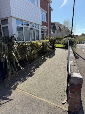 Une rue résidentielle bordée de maisons, avec un trottoir pavé et une clôture en métal.
