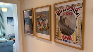 Trois affiches encadrées sont accrochées au mur, représentant des scènes de surf et comportant du texte.