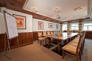 A conference room with a long table, chairs, a whiteboard, framed pictures, and a projector.