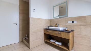 A modern bathroom with a wooden vanity, a white sink, and a mirror.