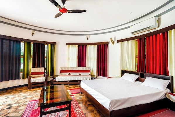 Habitación de hotel con cama, escritorio, silla, ventilador de techo y ventana con cortinas.