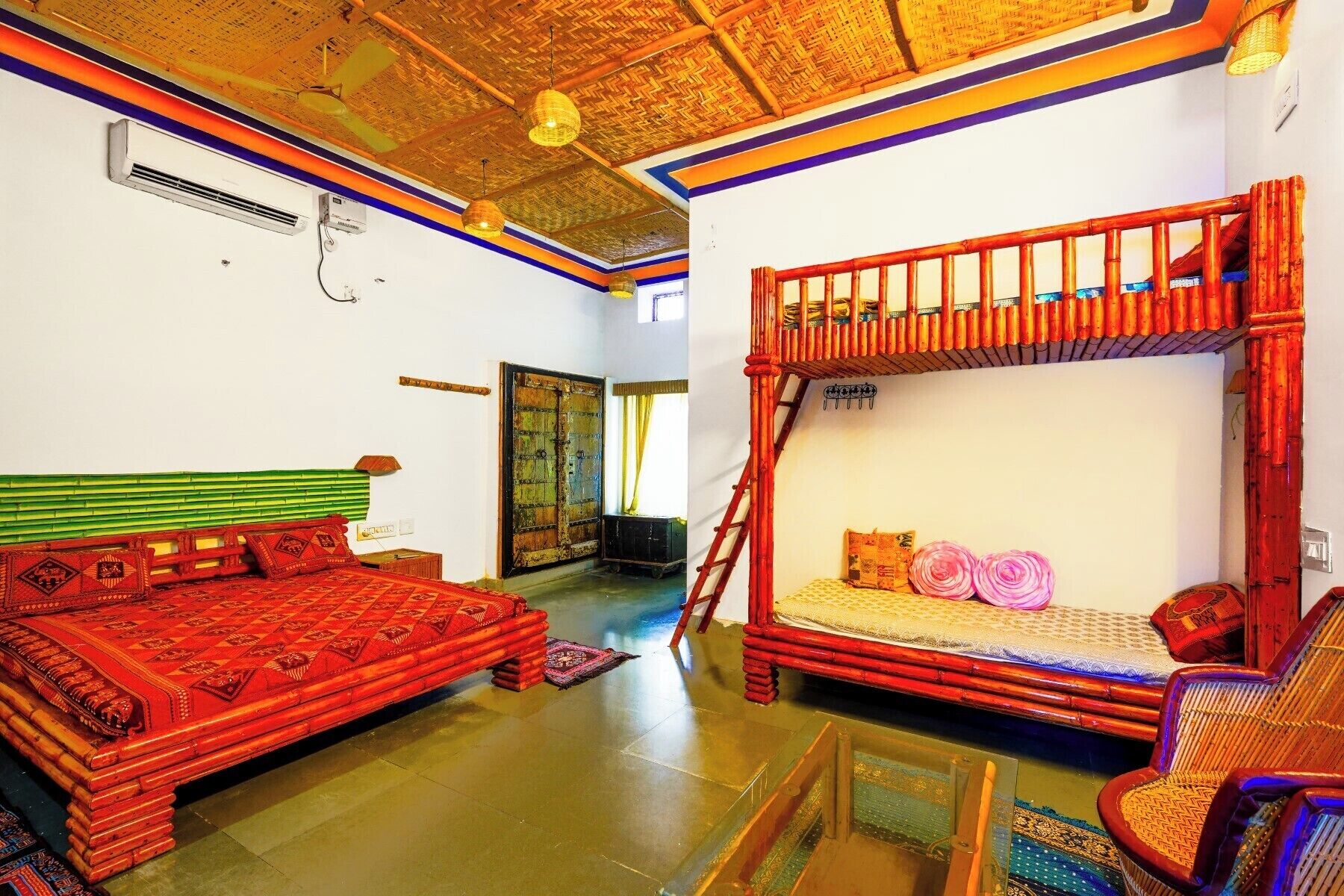 Habitación con dos camas, una escalera, una silla y un sillón de mimbre.