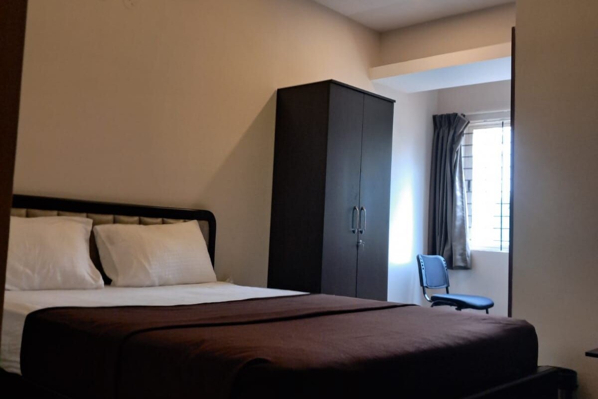 A bedroom with a bed, a wardrobe, a ceiling fan, and a window with curtains.