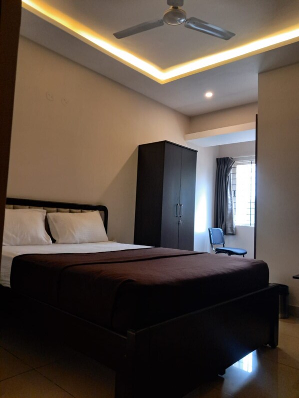 A bedroom with a bed, a wardrobe, a ceiling fan, and a window with curtains.