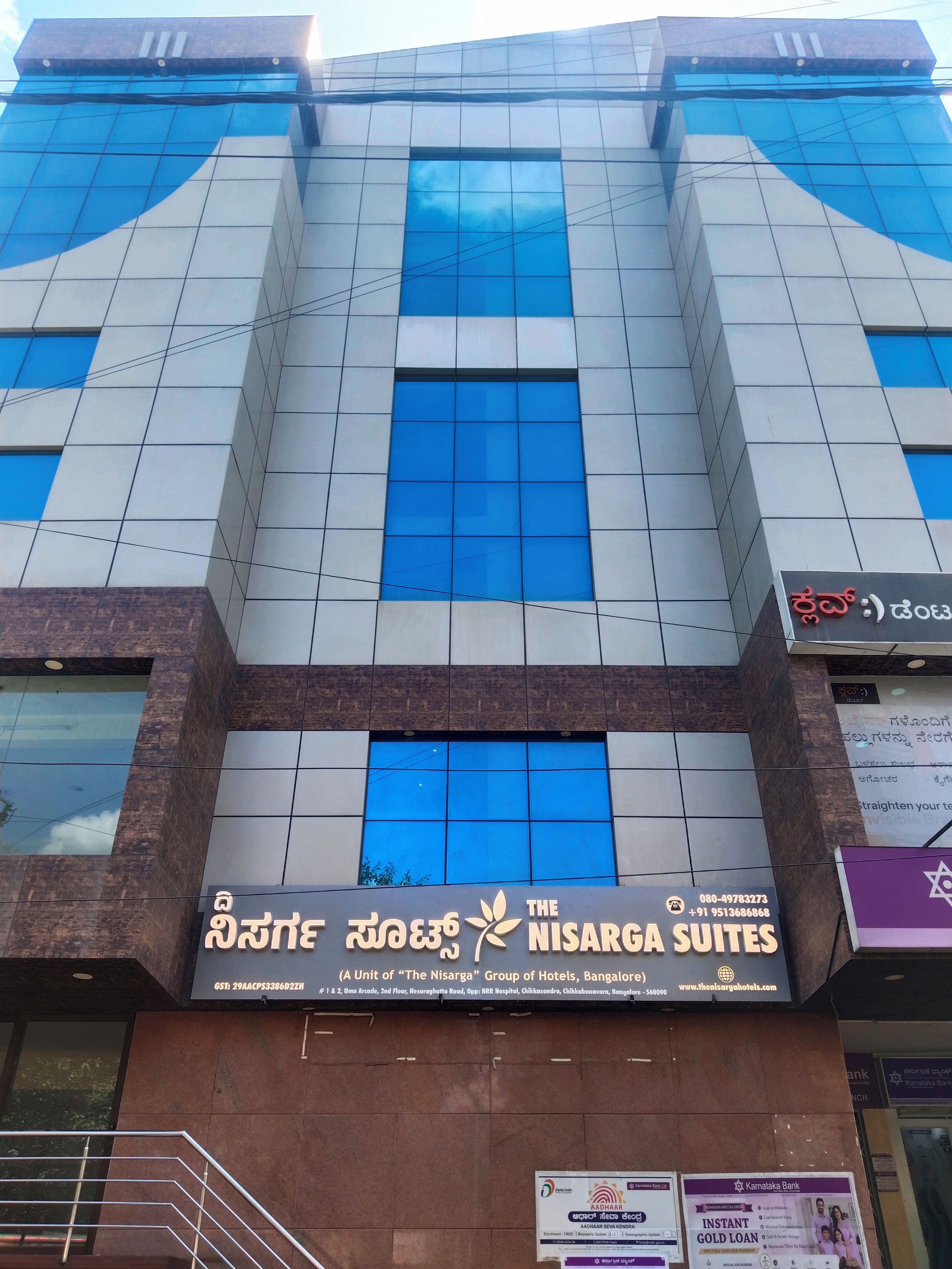 A hotel building with multiple windows and a sign for 'The Nisarga Suites.'