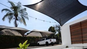 A patio area with a table, a potted plant, and a white vehicle parked in the background. - The Royal Bryanston (Sandton)