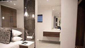 A modern bedroom with a bed, bedside table, and a nightstand. - The Royal Bryanston (Sandton)