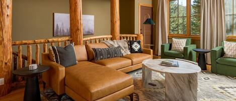 A cozy living room with a leather sofa, a round coffee table, and a green armchair.