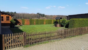 Ein Innenhof mit Holzzaun, Rasenfläche und einem Gebäude mit Holzfassade.