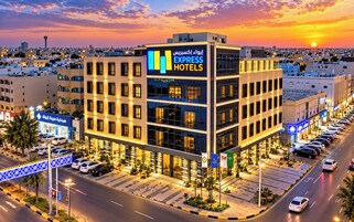 Un hotel de varios pisos con un letrero llamativo que dice 'Express Hotels' y un estacionamiento con varios automóviles.