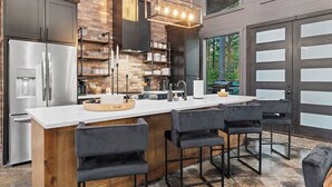 Una cocina moderna con una isla grande, taburetes de bar y vistas al exterior.