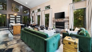 Una sala moderna con chimenea de piedra, sofás verdes y un televisor de pantalla plana.