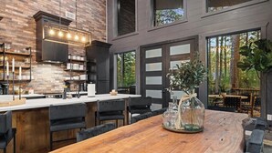 Una cocina moderna con una isla de madera, sillas negras y una mesa de comedor con un jarrón.