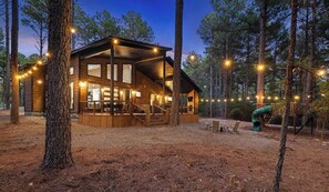 Eine Holzhütte mit großen Fenstern, einer Terrasse und Lichterketten.