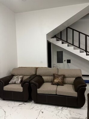 Ein modernes Wohnzimmer mit einer Couch, einer Treppe und einem Marmorboden.