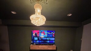 Ein Wohnzimmer mit Flachbildfernseher, Couch, Couchtisch aus Holz und einer Kristallleuchter.
