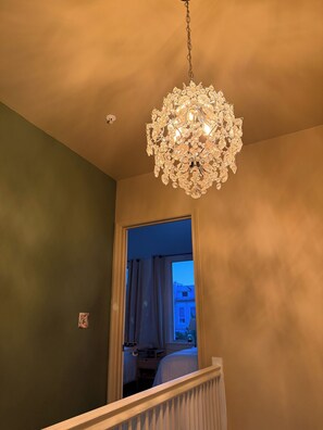 Un lustre à motifs de cristal est suspendu au plafond dans une pièce aux murs verts.