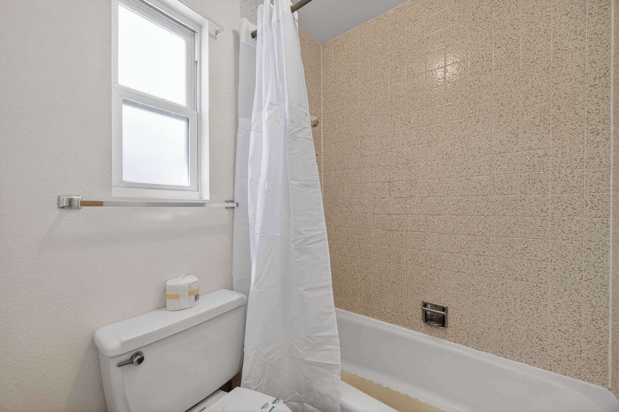 A bathroom with a white toilet, a bathtub, and a shower curtain.