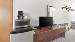 A kitchenette with a microwave, coffee maker, and refrigerator. A flat-screen TV is on a wooden dresser. - Eagle Motel Suite 226 (Manitou Springs)