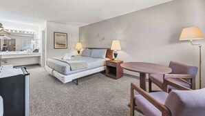 A hotel room with a bed, bedside tables, a desk, a chair, and a lamp. - Eagle Motel Suite 226 (Manitou Springs)