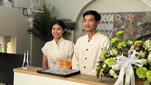 A reception desk with a tray of glasses, a decorative wall, and a floral arrangement.
