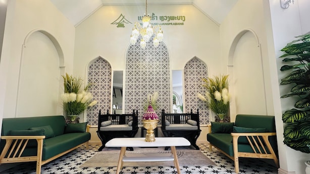 A lobby with a patterned floor, a chandelier, two sofas, a coffee table, and a decorative wall with a logo.