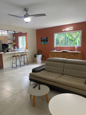 A modern living room with a sofa, a coffee table, and a TV. - Villa near Restaurants, Bars, Beach, Hiking, Pets allowed (Saint-Paul)