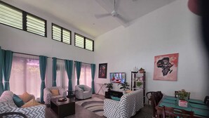 Una sala de estar con dos sofás, una mesa de centro, un televisor, una estantería y una mesa de comedor con sillas.
