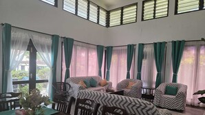 Una habitación con un conjunto de sofá, sillas, una mesa de comedor con individuales verdes y una planta en maceta.