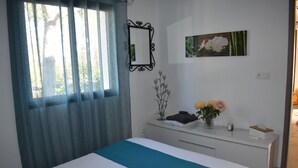 Une chambre à coucher avec un lit, une commode, un miroir et une fenêtre avec des rideaux.