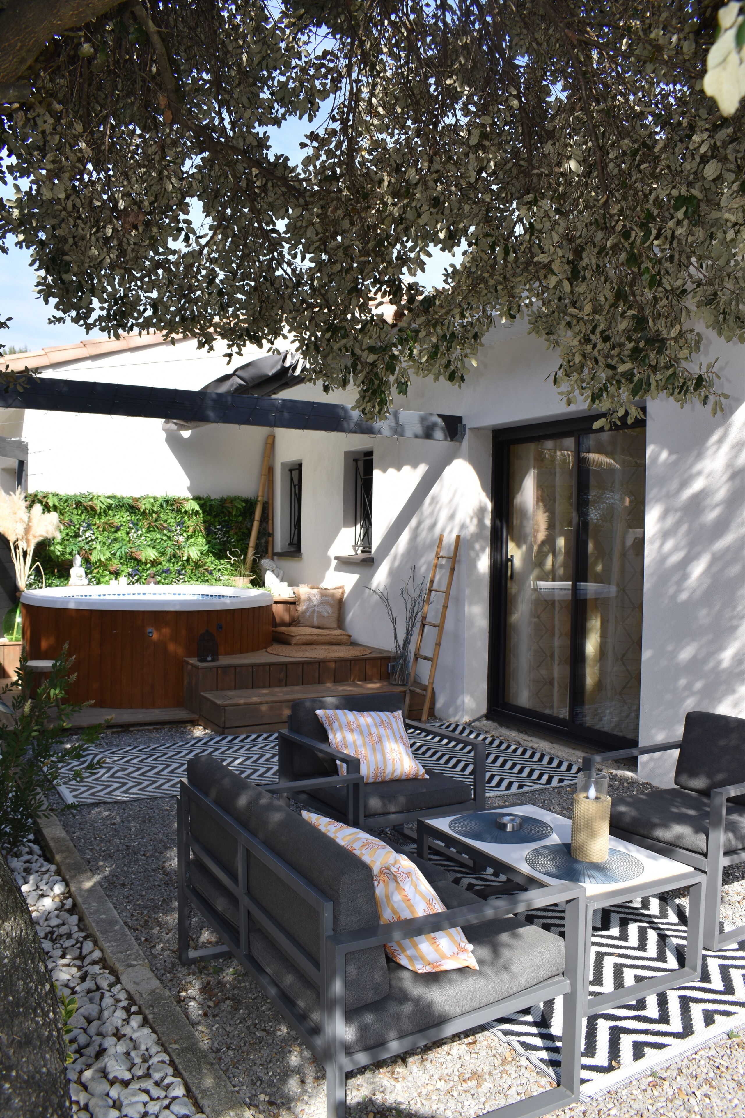 A patio with a hot tub, outdoor seating, and a patterned rug.